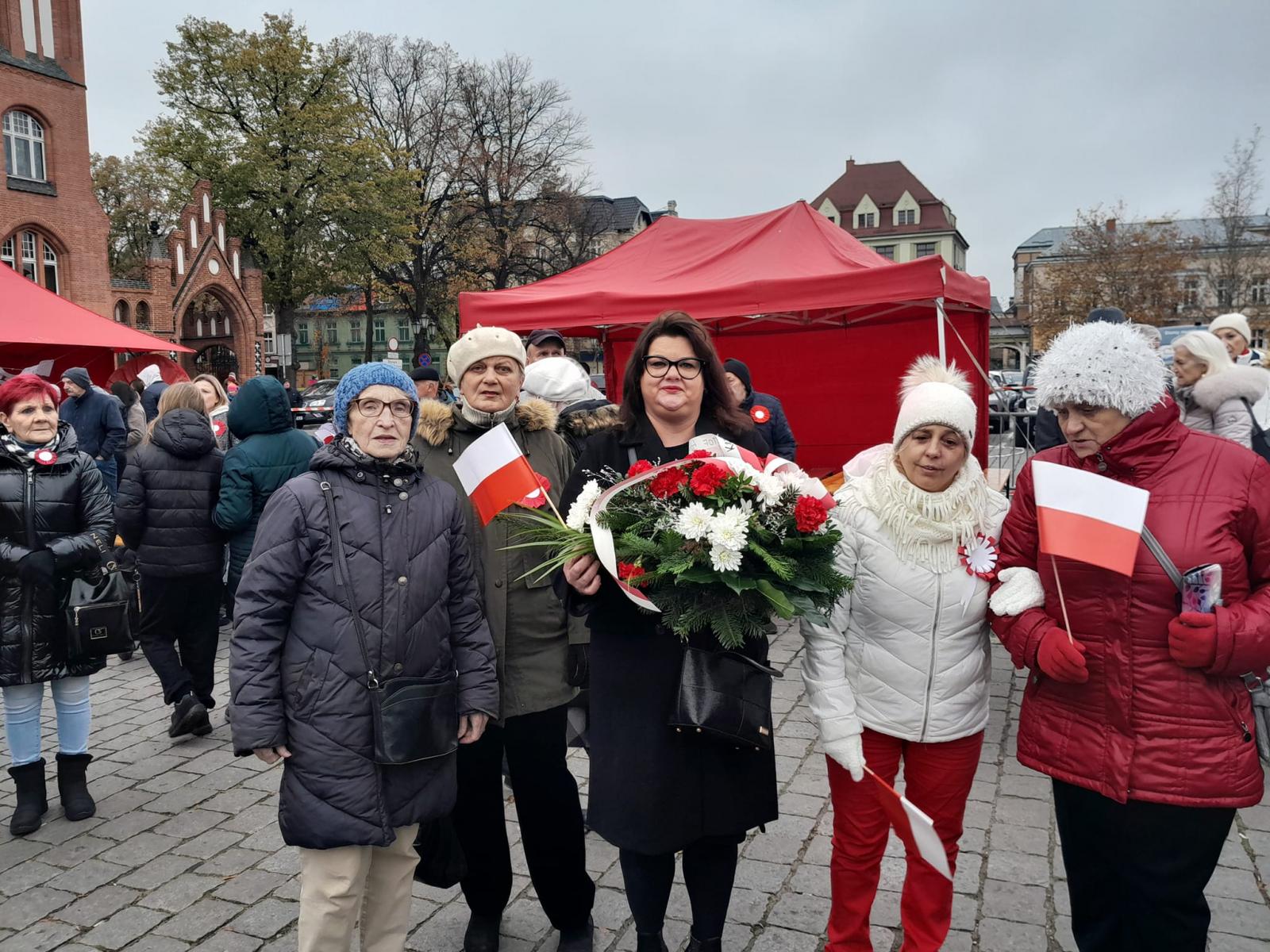 Seniorzy z Domu Sąsiedzkiego stoją przed Ratuszem w Słupsku. Obchodzą Dzień Niepodległości